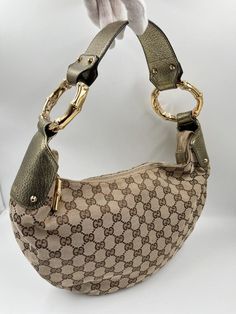 A Vintage Gucci Hobo made from brige canvas with the GG monogram. Gold metallic leather trim with gold embossed logo and gold hardware. Iconic bamboo detail on the shoulder strap and zip pull. The inside of the bag is in good condition and features an interior zipped pocket for valuables. The external fabric of this bag is also in very good condition. Inside there is the serial number on the back of the leather Gucci tab inside. Height: 21cm Width: 31cm Depth: 7cm Gg Monogram, Gucci Bamboo, Embossed Logo, Hobo Bag, Vintage Gucci, Gold Hardware, Shoulder Strap, Bamboo, Gucci