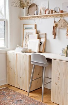 a desk with a chair and some pictures on the shelf above it in front of a window