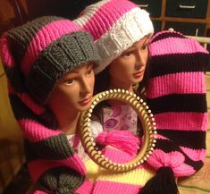 two mannequins wearing knitted hats and scarves holding a circular object