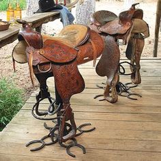 several different types of saddles are lined up on a wooden platform