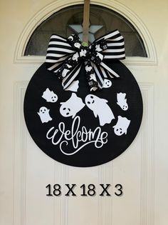 a welcome sign hanging on the side of a white door with black and white decorations