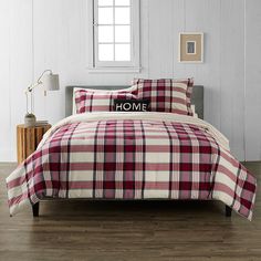 a red and white plaid comforter set on a bed in a room with wood floors