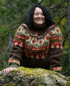 a woman standing on top of a moss covered tree trunk in the woods smiling at the camera