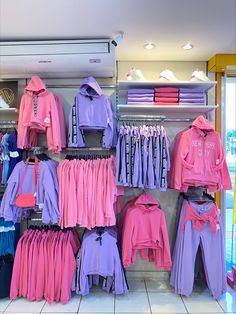 a clothing store display filled with pink and purple shirts, pants and handbages