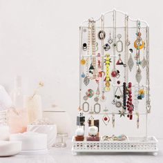 a white jewelry rack with lots of earrings hanging from it's sides on a table