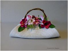 a white purse with flowers on it sitting on top of a table next to a wall