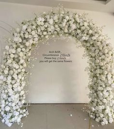 white flowers are arranged in an arch on the wall