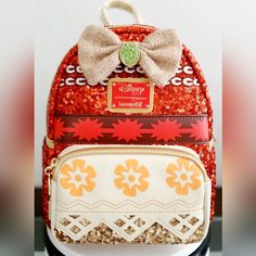 a red and white backpack with a bow on it's front, sitting on a table