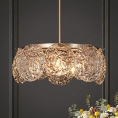 a chandelier hanging from the ceiling with flowers in front of it and an image of