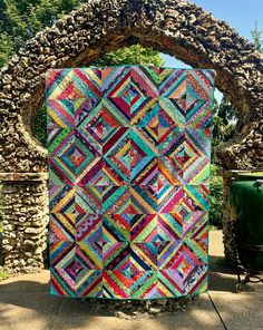 a colorful quilt hanging on the side of a stone arch