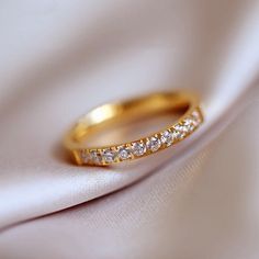 a gold wedding band with five diamonds on it's side sitting on a white cloth