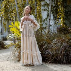 a woman standing in front of some trees wearing a dress with ruffles on it