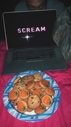 a plate full of cookies sitting in front of a laptop on a pink table cloth