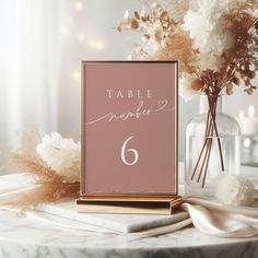 a table number sign sitting on top of a table next to some flowers and candles