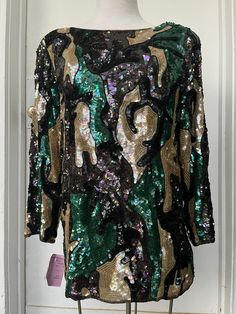 "Stunning vintage designer top with multicolor sequins. Looks even more stunning on.  Trimmed with beadwork of similar colors of green gold black and purple. Has shoulder pads and a 3.5\" slit on sides. New with tag from Nordstrom. Tag says large, but fits more like a medium. Measurements are 37\" chest 38\" waist 27\" long 21\" sleeve. Weighs 1 lb 11 oz but isn't too heavy or uncomfortable to wear." Multicolor Sequins, Designer Top, Sequin Blouse, St Martin, Black And Purple, Vintage Designer, Green Gold, Gold Black, Green And Gold