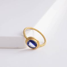 Description One-of-kind 18k yellow gold ring with a unique bi-color oval sapphire with darker and light blue hues, set in an east-west setting. The color of this sapphire is like seeing where the sky and the ocean meets at the horizon. This ring is in a rope design, adding a little more detail to every part of the ring. Details 18k Yellow Gold Size of sapphire – 7.1 x 6.1 x 2.8 mm (1.17 ct) Made in Japan *Please note that due to the natural quality of the stones, there may be inclusions, cracks, Gold Oval Blue Topaz Birthstone Ring, Oval Gold Sapphire Birthstone Ring, Blue Oval Birthstone Ring With Bezel Setting, Gold Oval Sapphire Birthstone Ring, Gold Tanzanite Sapphire Ring, Modern Oval Tanzanite Sapphire Ring, Gold Sapphire Birthstone Ring With Rose Cut Diamonds, Modern Sapphire Ring With Rose Cut Diamonds, Modern Sapphire Ring Oval Cabochon Polished Finish