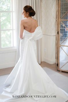 a woman in a white wedding dress looking out the window