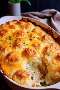 a casserole dish with cheese and meat in it on a table next to a potted plant