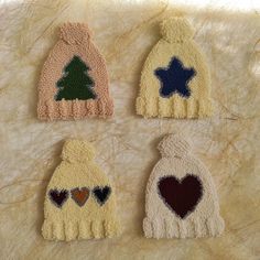 three knitted hats with hearts and stars on the top, one has a tree in the middle