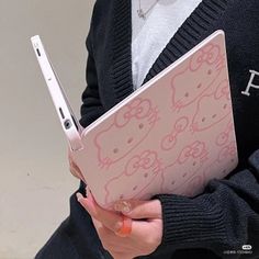 a woman holding an open laptop computer in her hands with hello kitty decals on it