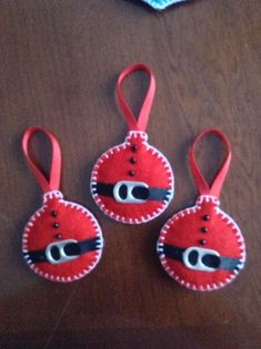 three red and black ornaments sitting on top of a wooden table