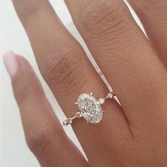 a woman's hand with a diamond ring on top of her finger and an engagement band