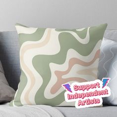 a green and white pillow with the words support independent artists on it, sitting on a couch