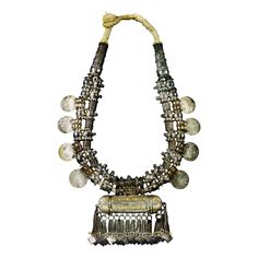 Stunning and rare Omani tribal necklace in gold and silver featuring eight Burgau thalers dated 1780. 19th century. Very good condition. Preserved and professionally framed. Dimensions of the necklace: 52 x 30 x 3 Dimensions of the frame: 70 x 47 x 5 Secure shipping. This fine Omani necklace of silver and gold comprises two strands of spiky, seed pod-like silver beads; gold-wrapped beads; eight silver Maria Theresa thaler coins; and a large silver and gold amulet box, with multiple chain tassels each of which finishes with a square-shaped pendant cut from sheet silver. The cigar-shaped amulet box called hirz would have contained some Koranic verse or religious text. Such a spectacular display of wealth would only have been worn at times of important festivities such as marriage celebration Gold Amulet, Silver Gold Necklace, Maria Theresa, Seed Pod, Historical Jewellery, Local Jewelry, Rope Necklace, Oman, Metal Jewelry