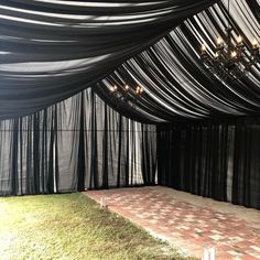 an outdoor stage with black drapes and chandelier hanging from it's ceiling