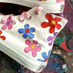 a pair of white shoes with colorful flowers painted on them