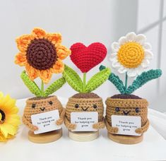 three crocheted vases with flowers in them on a table next to a sunflower