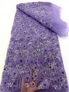 a woman's hand is holding onto a purple cloth with beads and sequins on it