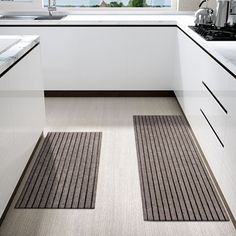 a kitchen with two mats on the floor and a sink in front of a window