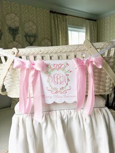 a baby's crib with pink bows and a monogrammed pillow on it