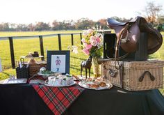 a table topped with baskets filled with food next to a horse and rider's saddle