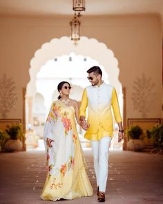 a man and woman in yellow outfits walking down a hall holding each other's hands