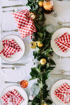 the table is set with red and white checkered napkins, place settings, silverware