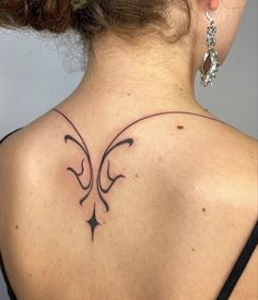 the back of a woman's neck with a tattoo design on her left shoulder