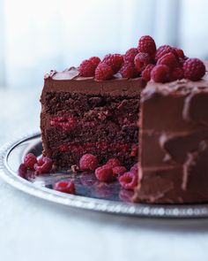 a piece of chocolate cake with raspberries on the side and one slice missing