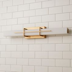 a bathroom light mounted on the side of a white brick wall