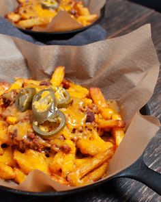 two baskets filled with cheesy pasta and cheese on top of a wooden table