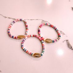 - Multicolored beaded bracelet with gold shell - Stretchy band - One size Multicolor Friendship Bracelets With Gold Beads For Beach, Multicolor Gold Beads Friendship Bracelet For Beach, Pink Bracelets With Gold Beads For Beach, Gold Beaded Bracelets With Letter Beads For Beach, Gold Friendship Bracelets With Gold Beads For Beach, Adjustable Gold Stretch Bracelet For Vacation, Casual Gold Stretch Bracelet For Beach, Heishi Beads Stretch Bracelet With Tiny Beads For Beach, Multicolor Bracelets With Gold Beads For Beach