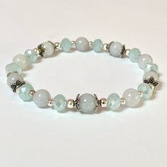 This genuine Aquamarine bracelet is 8" It is created with 8mm natural Aquamarine beads which are selected to match as best possible. To add a little sparkle are glass crystal faceted beads and silver filigree end caps.  Aquamarine is a stone of courage with calming energy to reduce life's stress and bring quiet to the mind.  Helps you connect with your inner-self and intuition. 🌹 Each piece of jewelry will come to you with the name of your stone and a brief description of the healing energy it Silver Hypoallergenic Stretch Bracelet, Silver Hypoallergenic Stretch Bracelet For Healing, Silver Beaded Bracelets For Healing, Healing Silver Beaded Bracelets With Faceted Beads, Spiritual Silver Jade Beaded Bracelets, Silver Jade Bracelet With Natural Stones, Spiritual Silver Beaded Jade Bracelets, Silver Jade Beaded Bracelets With Gemstones, Silver Jade Beaded Bracelet With Natural Stones