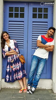 a man and woman standing next to each other in front of a blue door with shutters