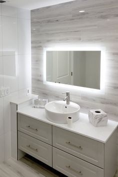 a bathroom with a sink, mirror and toilet paper dispenser on the counter