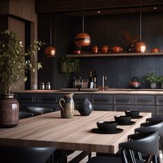 a wooden table surrounded by black chairs in a room with shelves and potted plants