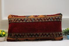 a red pillow sitting on top of a white floor next to a potted plant