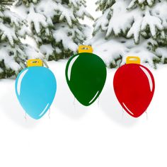 three christmas baubles in the snow next to evergreen trees