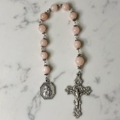 Handmade traditional Catholic single decade tenner rosary using light pink dyed jade smooth round stone beads. Antique silver daisy bead caps on every bead with additional flower bead caps on Our Father bead. Antique silver Our Lady of Schoenstatt Medal with Ornate Fleur-de-Lis Crucifix. Hail Mary beads are 8mm with the Our Father bead being 10mm. Designed to be used and/or displayed. Measures about 10" long. This rosary would make a beautiful gift for a baby shower, Baptism, First Communion, Reconciliation, Confirmation or any other special event or occasion. Comes in a beautiful black velvet pouch. I ship same or next business day. All of my rosaries are one of a kind and are my own personal creation. Photos are a part of the description-you will receive the exact rosary pictured. Please Pink Rosary Beads, Handmade Pink Rosary For Healing, Handmade Pink Rosary With Round Beads, Pink Beaded Spiritual Rosary, Pink Rosary With 8mm Round Beads, Handmade Pink Rosary Bracelet For Healing, Pink Hand-strung Spiritual Rosary Bracelet, Pink Spiritual Rosary Bracelet With 8mm Beads, Pink Beaded Rosary With Round Beads