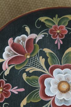 an artistically painted wooden plate with flowers on it